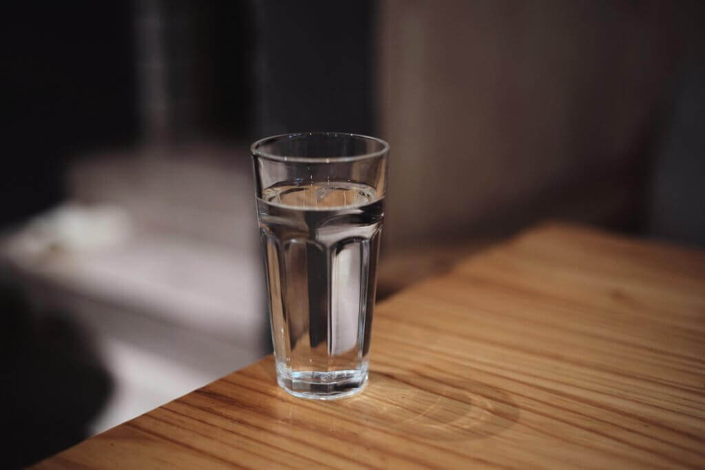 A clear glass of water, symbolizing hydration for skin health.