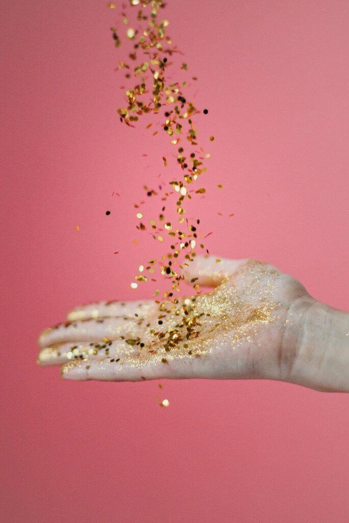 A hand holding colorful confetti, symbolizing celebration and positive expectation.
