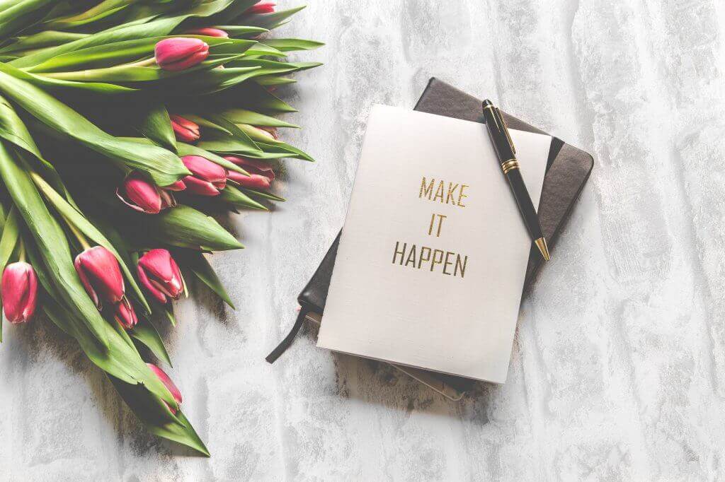 A planner book with the words 'Make It Happen' on the cover.
