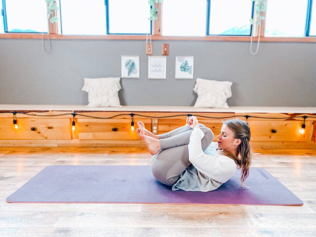 Woman in Knees to Chest pose to relieve gas and bloating.