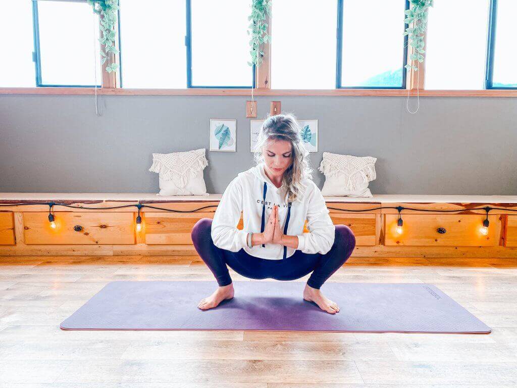 Woman in a deep Yogi Squat to open the hips.