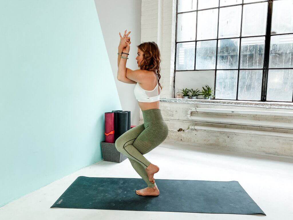 Woman balancing in Eagle Pose.