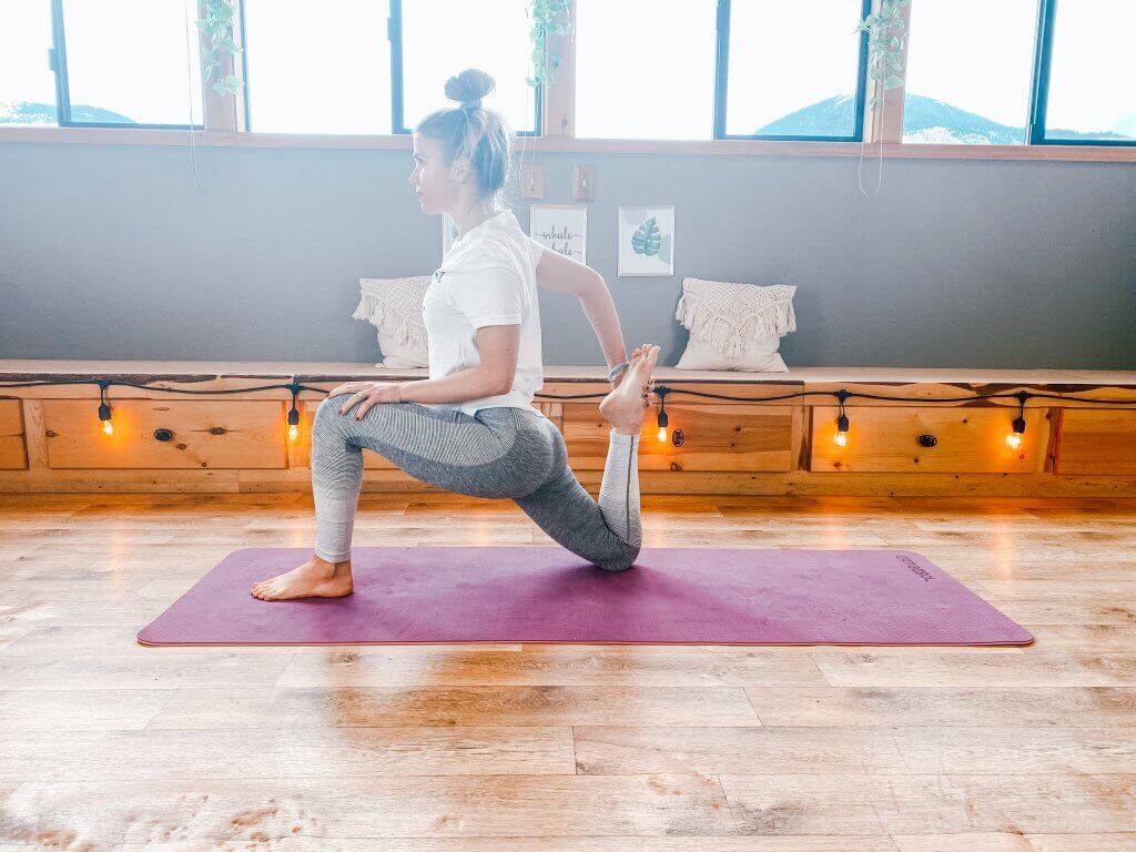 Woman in a low lunge variation, stretching the quad by holding the back foot.