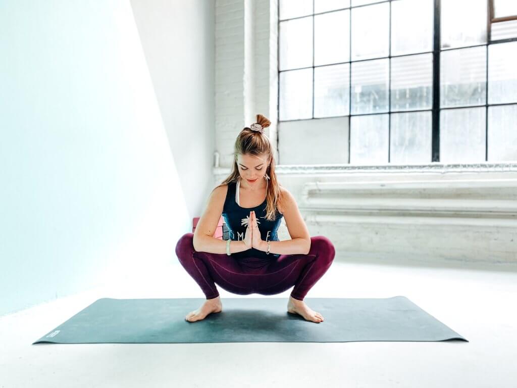 Woman in a deep Yogi Squat or Malasana.