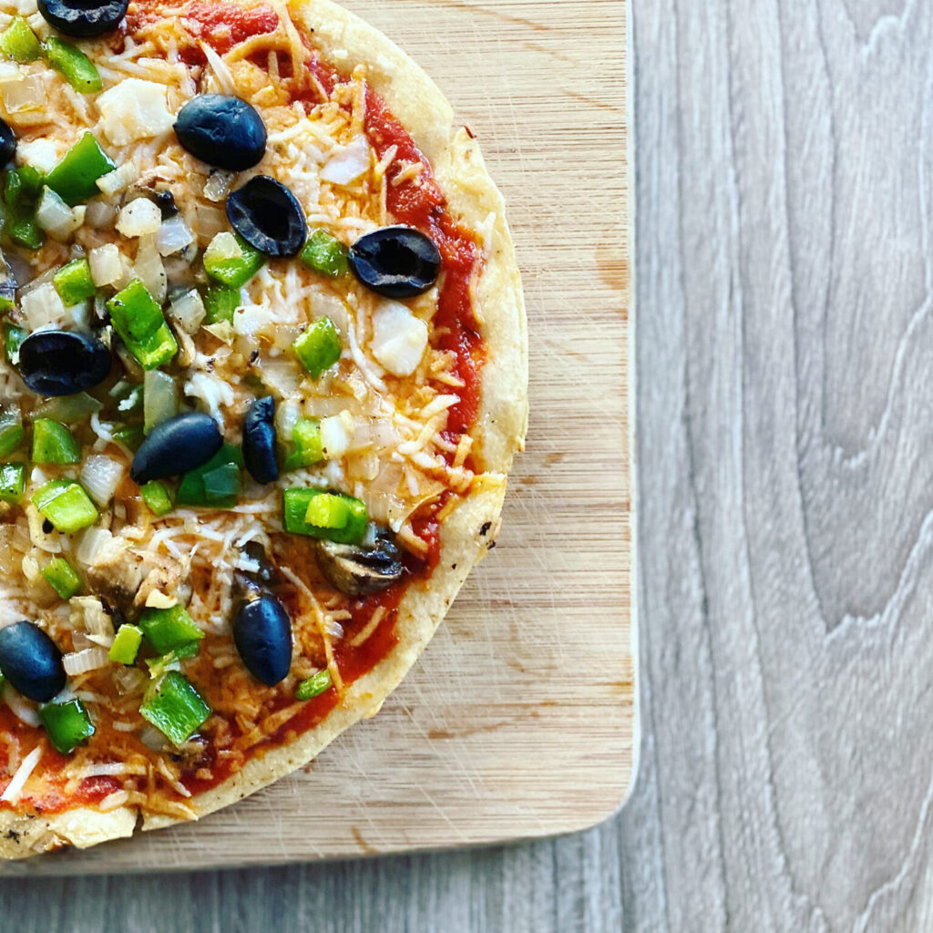 A freshly baked vegan and gluten-free pizza with a chickpea crust and various vegetable toppings.