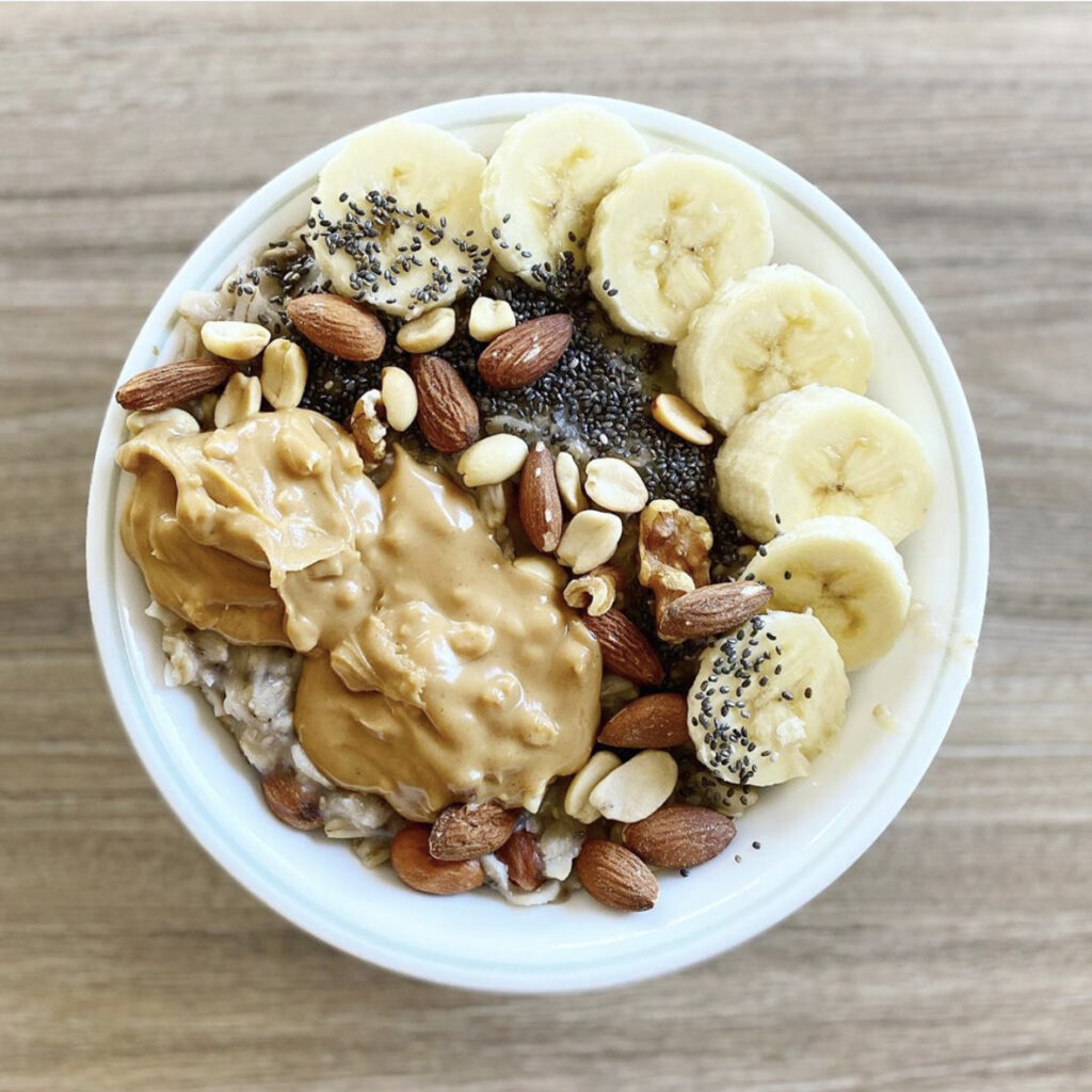 A delicious bowl of vegan oatmeal topped with fresh banana, nuts, and seeds.