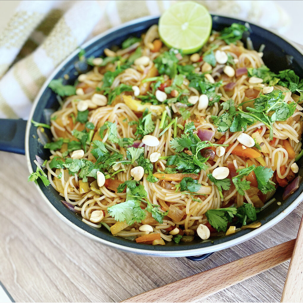 A delicious bowl of vegan Thai noodles with fresh vegetables and peanuts.