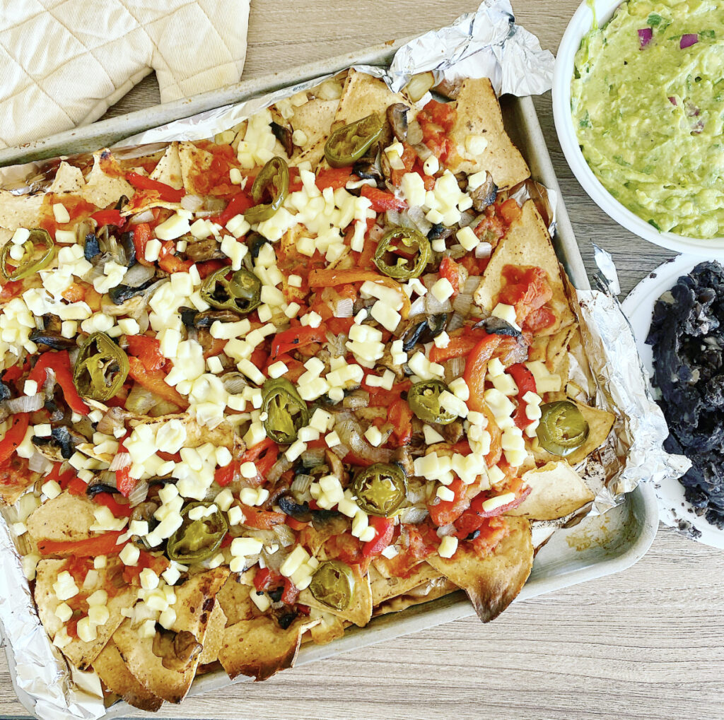 A large platter of delicious vegan nachos loaded with toppings.
