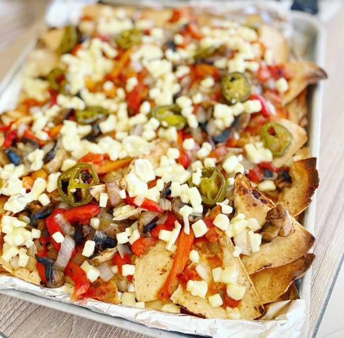 A close-up shot of vegan nachos with melted cheese and fresh toppings.